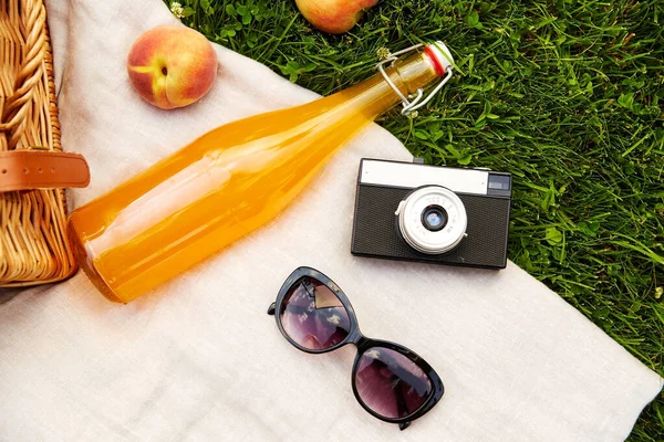 Cesta de piquenique, garrafa de suco, óculos de sol e câmera — Fotografia de Stock