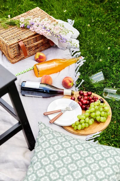 Jedzenie, napoje i kosz na kocu piknikowym na trawie — Zdjęcie stockowe