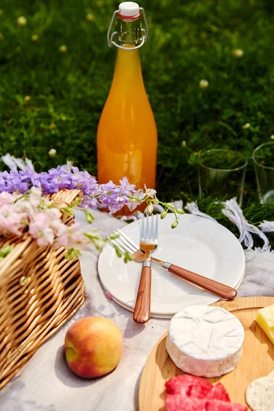 Essen, Getränke und Korb auf Picknickdecke im Gras — Stockfoto