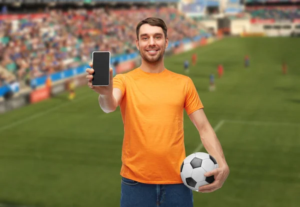 Футбольный болельщик со смартфоном и футбольным мячом — стоковое фото