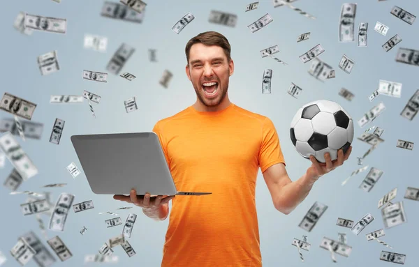 Hombre feliz con pelota de fútbol y portátil sobre el dinero — Foto de Stock