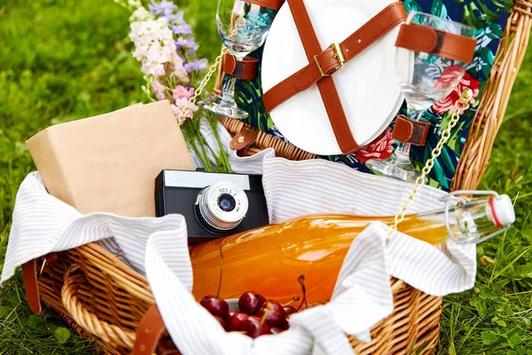 Suco, cereja, livro e câmera em cesta de piquenique — Fotografia de Stock