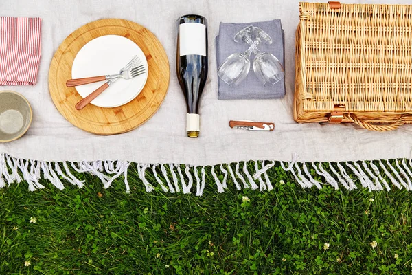 Keranjang, crockery dan botol anggur di atas selimut piknik — Stok Foto
