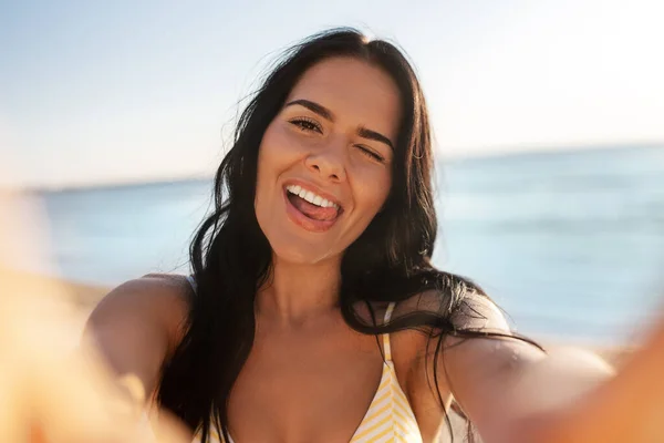 Usmívající se žena v bikinách při selfie na pláži — Stock fotografie
