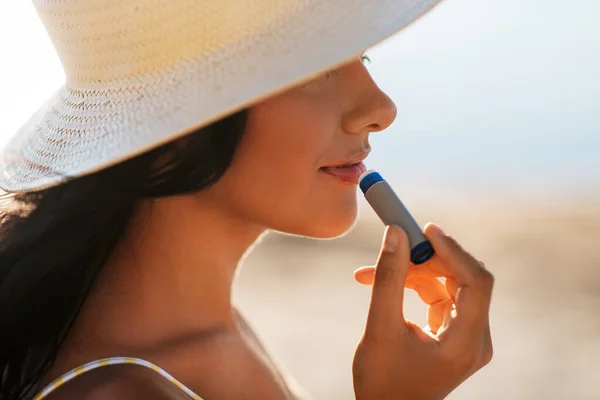Mulher sorridente em biquíni com bálsamo labial na praia — Fotografia de Stock
