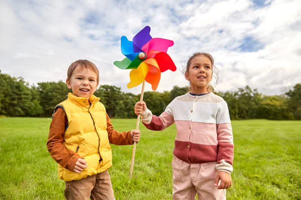 Crianças felizes brincando com pinwheel no parque — Fotografia de Stock