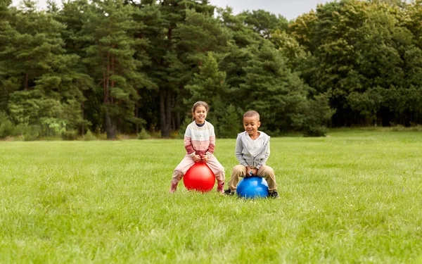 Glada barn studsar på tratten bollar i parken — Stockfoto