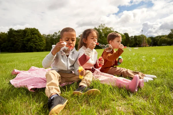 Grupo de niños soplando burbujas de jabón en el parque —  Fotos de Stock