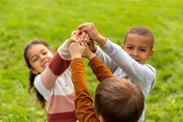 Grupo de crianças empilhando as mãos no parque — Fotografia de Stock