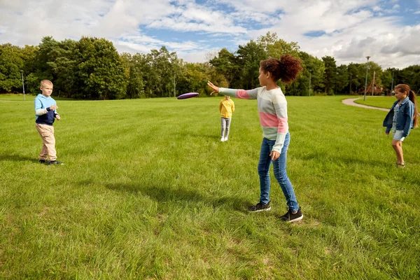 Crianças felizes brincando com disco voador no parque — Fotografia de Stock
