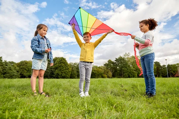 Щасливі діти з повітряним змієм грають у парку — стокове фото