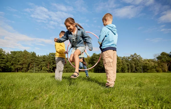 Счастливые дети играют в игру с обручем хула в парке — стоковое фото