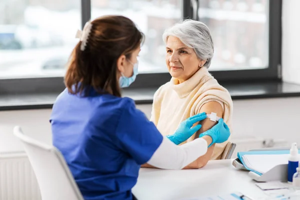 Sjuksköterska applicera medicinplåster på vaccinerad kvinna — Stockfoto