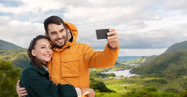 Pár se selfie na telefonu přes irskou krajinu — Stock fotografie