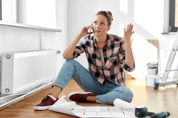Woman with blueprint calling on smartphone at home — Stock Photo, Image