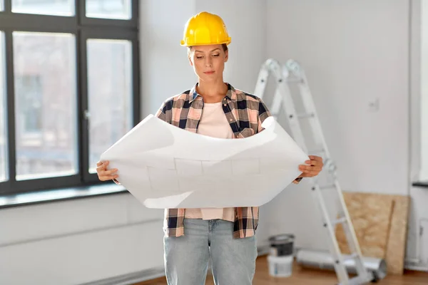 Woman in helmet with blueprint at home — 图库照片