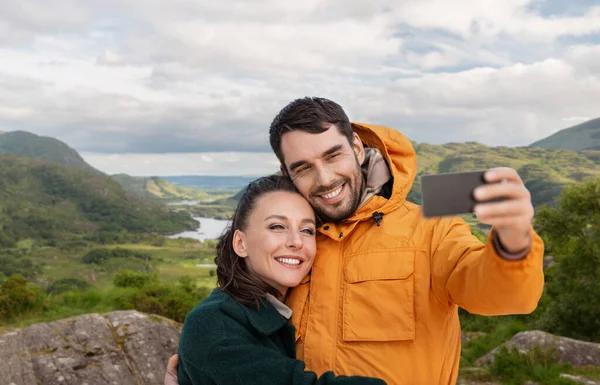 Пара делает селфи по телефону над ирландским ландшафтом — стоковое фото