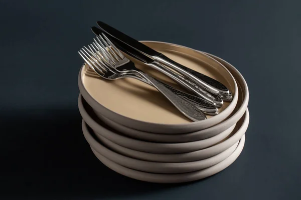Płyty ceramiczne, widelce i noże na czarnym stole — Zdjęcie stockowe