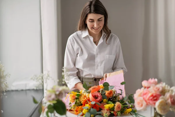 Mujer envolviendo flores a papel artesanal en casa —  Fotos de Stock