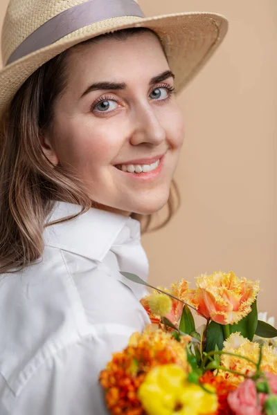 Mujer feliz en sombrero de paja sosteniendo ramo de flores — Foto de Stock