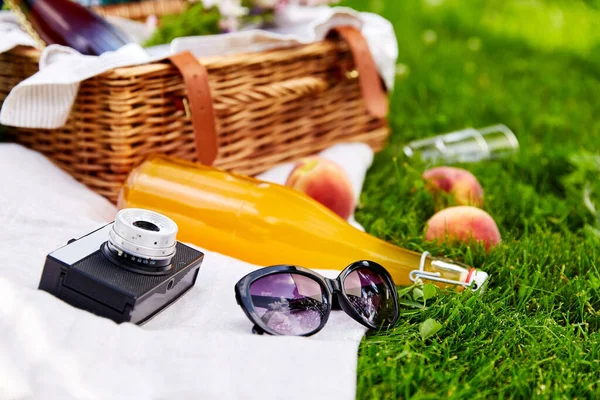 Сонцезахисні окуляри, кошик для пікніка, пляшка соку та камера — стокове фото