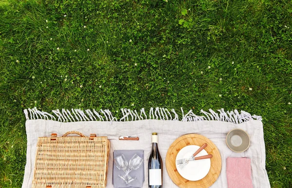 Keranjang, crockery dan botol anggur di atas selimut piknik — Stok Foto