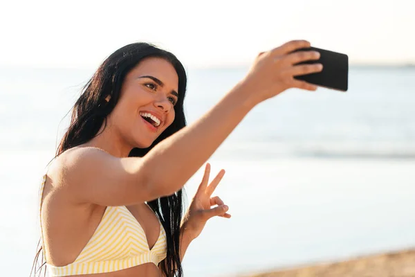 Lächelnde Frau im Bikini macht Selfie am Strand — Stockfoto