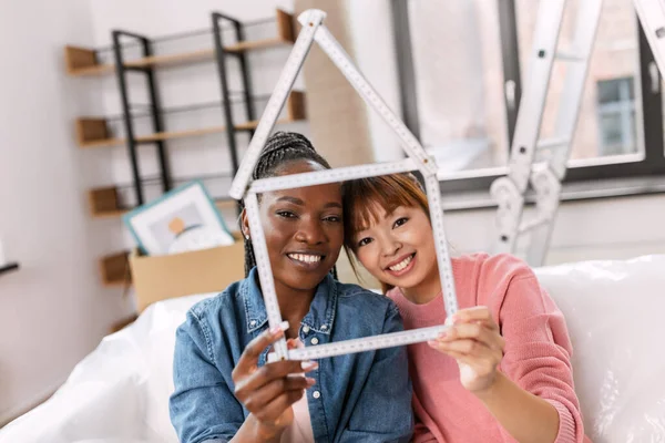 Mujeres sonrientes felices con regla en forma de casa —  Fotos de Stock