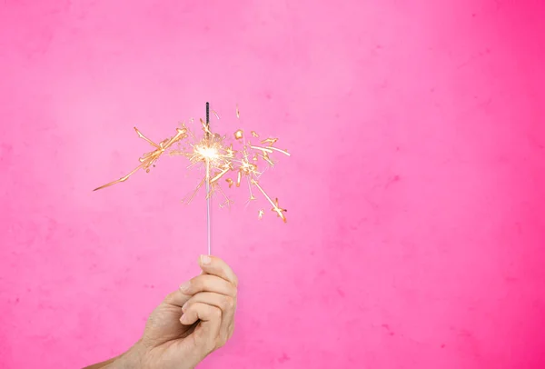 Mão com brilho queimando sobre fundo rosa — Fotografia de Stock