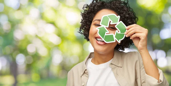 Счастливая женщина смотрит через зеленый знак переработки — стоковое фото