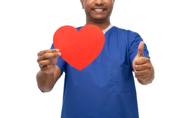 Médico masculino com coração vermelho mostrando polegares para cima — Fotografia de Stock