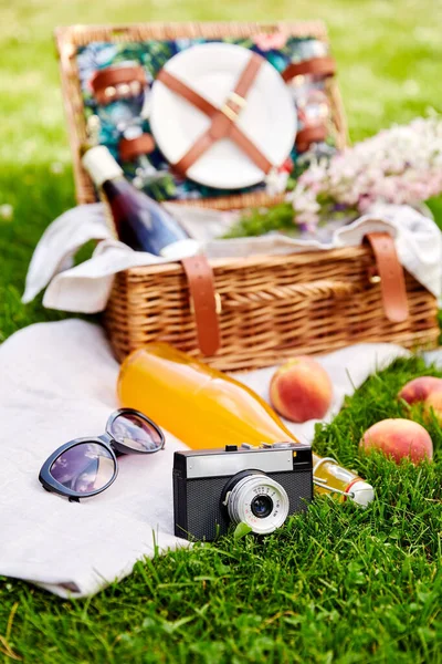 Câmera, cesta de piquenique, garrafa de suco e óculos de sol — Fotografia de Stock