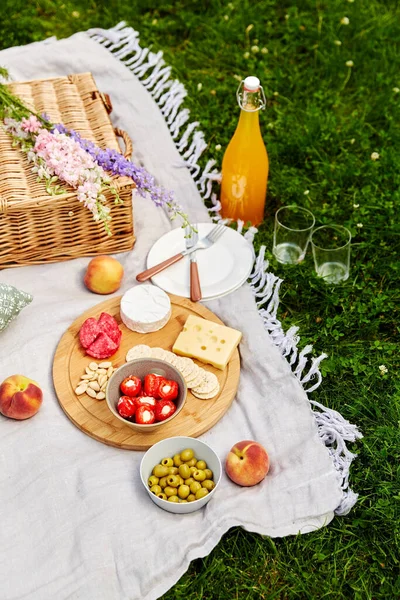 Comida, bebidas e cesta em manta de piquenique na grama — Fotografia de Stock