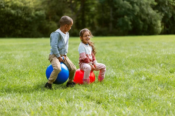 Niños felices rebotando en las bolas de la tolva en el parque —  Fotos de Stock