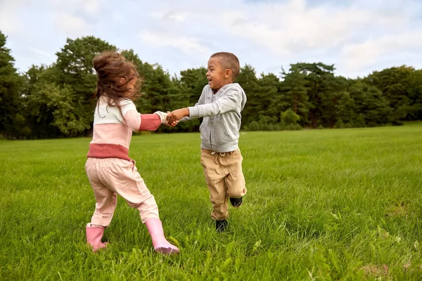 Χαρούμενο αγοράκι και κορίτσι διασκεδάζουν στο πάρκο — Φωτογραφία Αρχείου