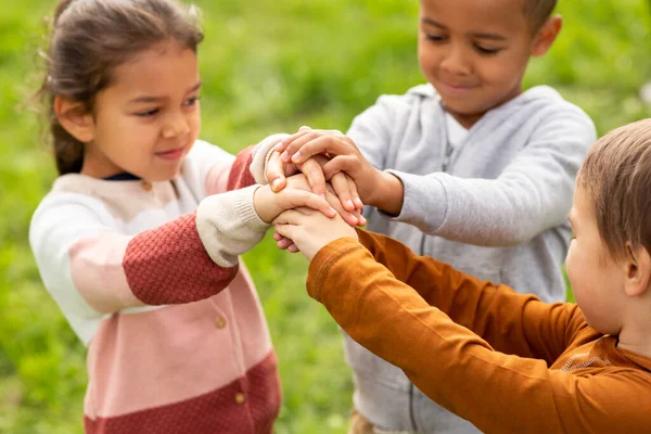 Grupo de crianças empilhando as mãos no parque — Fotografia de Stock
