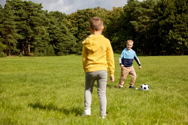 Счастливые мальчишки с мячом играют в футбол в парке — стоковое фото