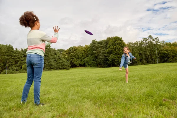 Счастливые девушки играют с летающим диском в парке — стоковое фото