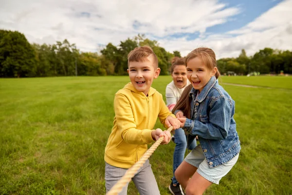 Niños felices jugando tirón de juego de guerra en el parque —  Fotos de Stock