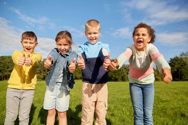 Gelukkig kinderen tonen duimen omhoog in park — Stockfoto