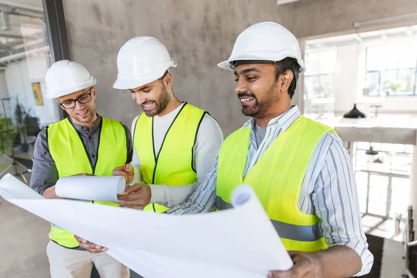 Arquitectos en cascos con plano en la oficina —  Fotos de Stock