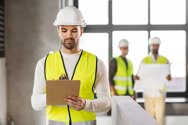 Arquiteto masculino no capacete com prancheta no escritório — Fotografia de Stock