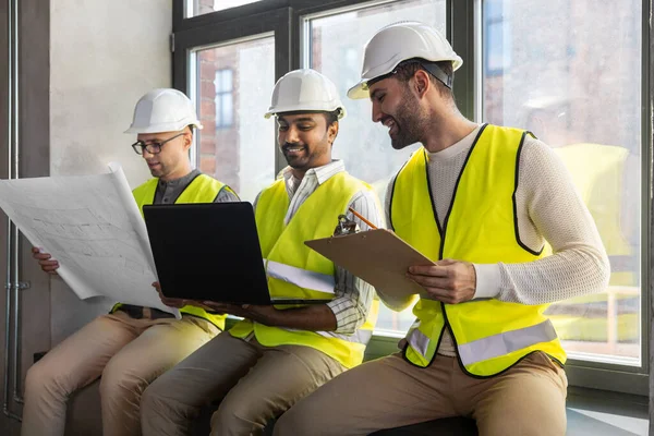 Arquitectos masculinos en cascos con portátil en la oficina — Foto de Stock