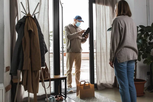 Voedsel levering man met masker met tablet pc en vrouw — Stockfoto