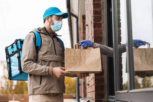 Homem de entrega de alimentos em máscara dando ordem ao cliente — Fotografia de Stock