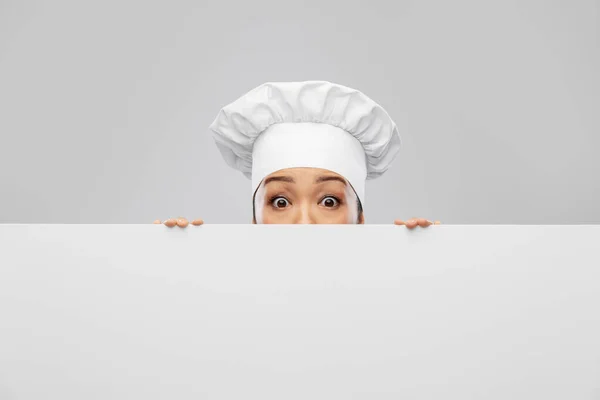 Chef feminino espreitando por trás da tábua branca — Fotografia de Stock