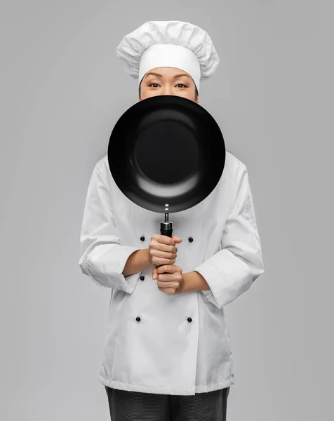 Female chef peeking out from behind frying pan — Stock Photo, Image