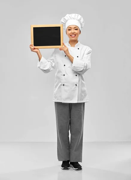 Sorridente chef feminino segurando quadro preto — Fotografia de Stock