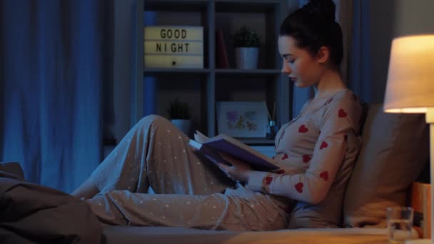 Adolescent fille lecture livre dans lit la nuit — Video