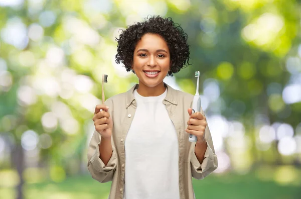 Vrouw vergelijken van houten en elektrische tandenborstels — Stockfoto